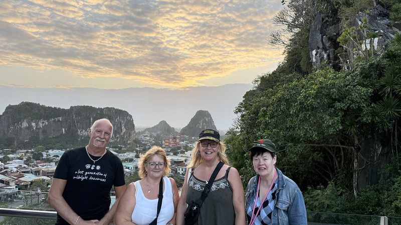 Tony, Eleanor, Susan and Sarah in front of a view from the top of the Marble mountain, in the background you can see the setting sun and more limestone hills/mountains