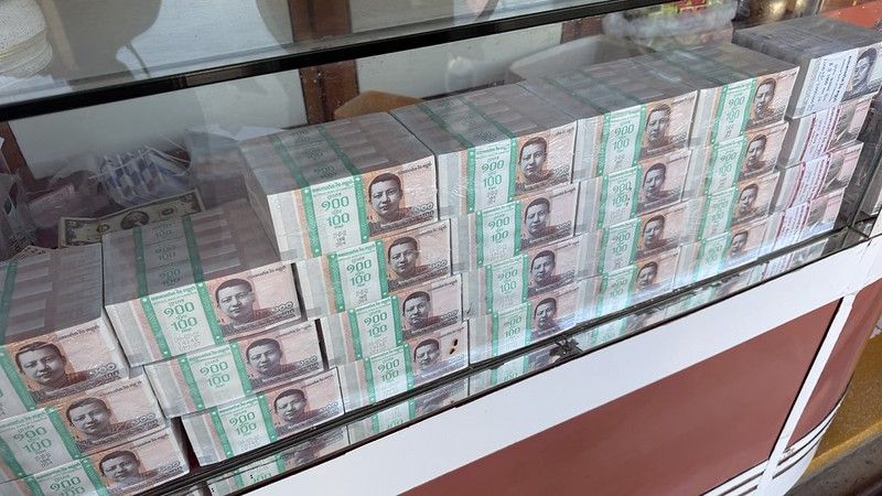 A glass cabinet containing many 1000 100 riel notes