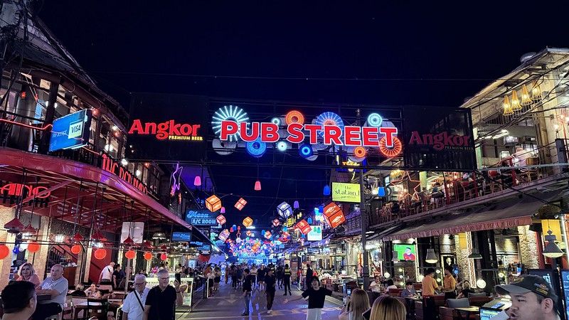 An asian street with many lanterns and hundreds of lights in in big illuminated letters above the street reads Pub Street